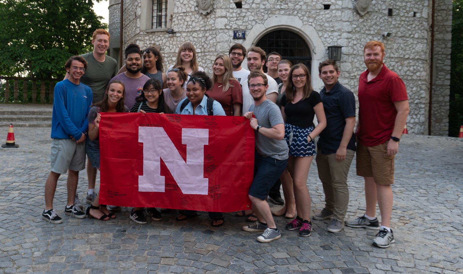 Students posing with a Nebraska flag in front of a castle.
